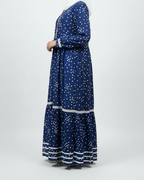 Woman wearing a blue dress with white patterns on a white background